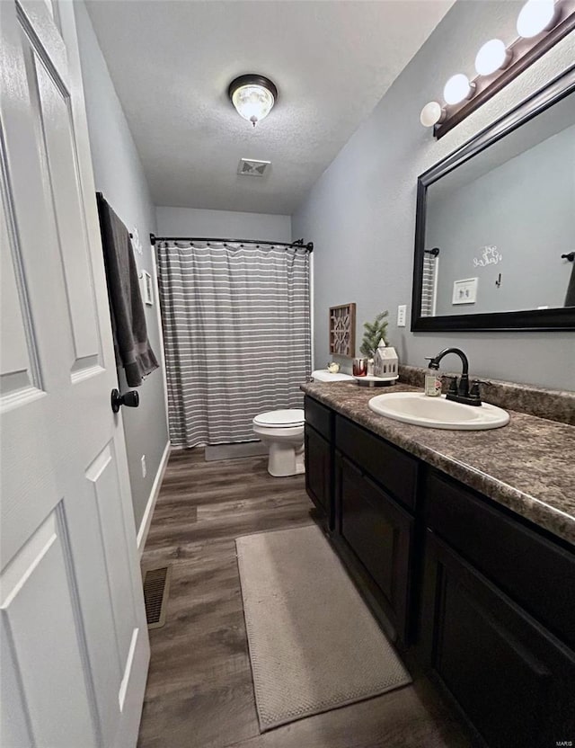 bathroom featuring a shower with curtain, a textured ceiling, toilet, vanity, and hardwood / wood-style flooring