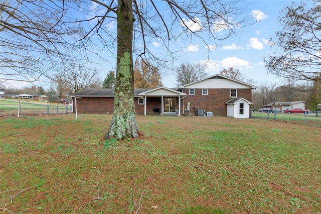 back of house with a storage shed and a yard