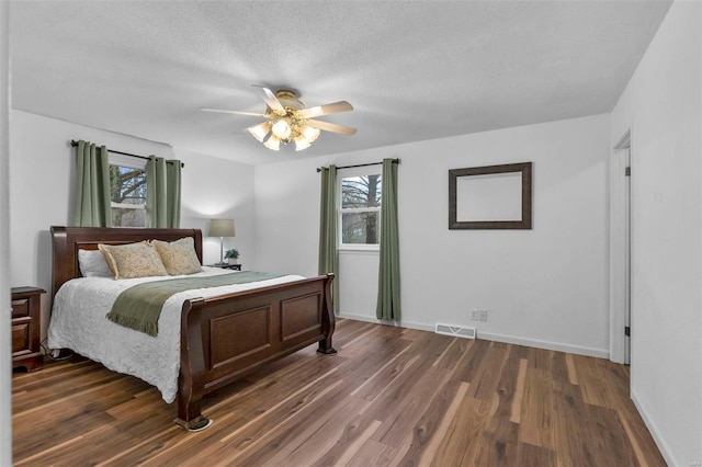 bedroom with ceiling fan, a textured ceiling, and dark hardwood / wood-style flooring