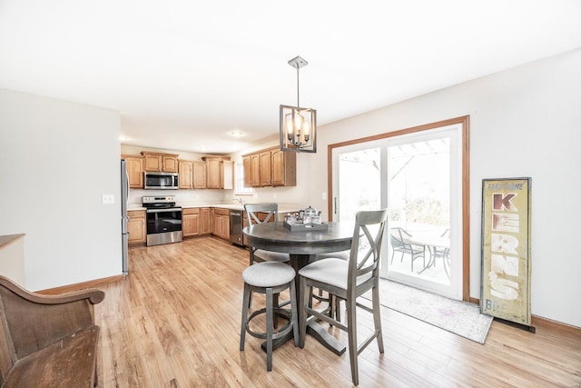 dining room with light wood-type flooring, plenty of natural light, and a notable chandelier