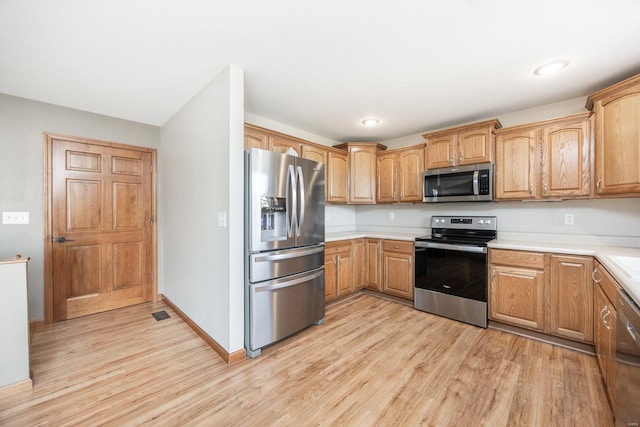 kitchen featuring appliances with stainless steel finishes and light hardwood / wood-style flooring