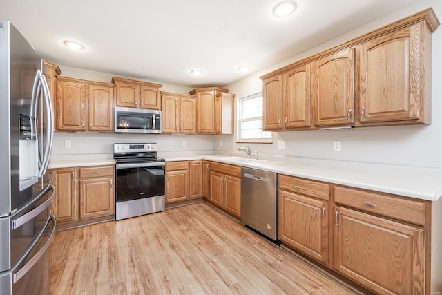 kitchen with light wood-type flooring, appliances with stainless steel finishes, and sink