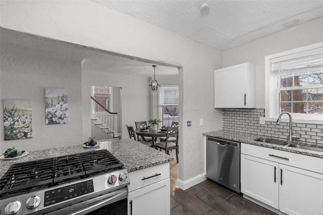 kitchen with white cabinets, sink, dark hardwood / wood-style floors, dark stone countertops, and appliances with stainless steel finishes