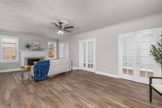 living room with a healthy amount of sunlight, wood-type flooring, a fireplace, and french doors