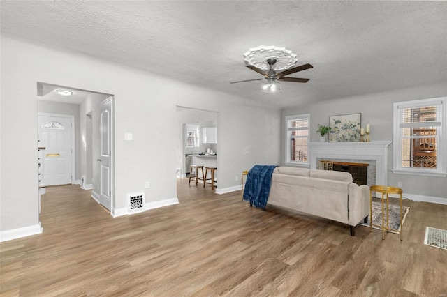 living room featuring a textured ceiling, light wood-type flooring, and ceiling fan