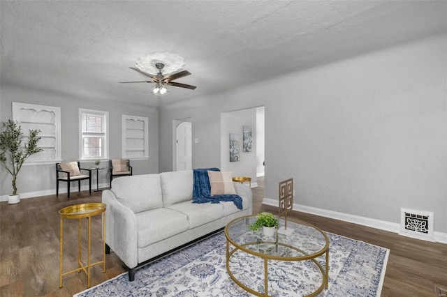 living room with ceiling fan, dark wood-type flooring, and a textured ceiling