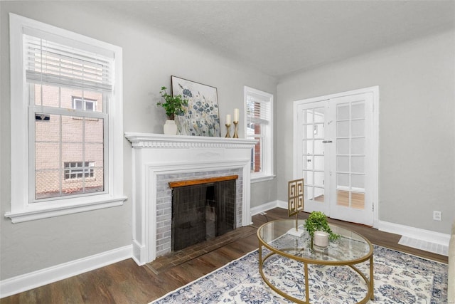 living room featuring dark hardwood / wood-style floors, french doors, a textured ceiling, and a brick fireplace