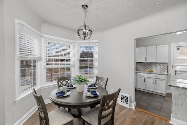 dining room featuring plenty of natural light, dark wood-type flooring, a textured ceiling, and an inviting chandelier