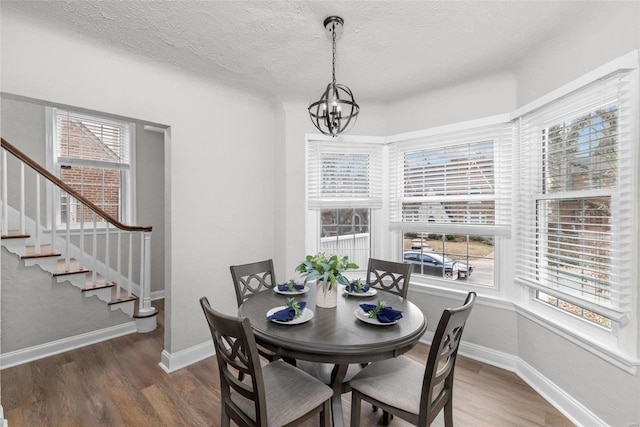 dining room with a textured ceiling, an inviting chandelier, a wealth of natural light, and dark wood-type flooring