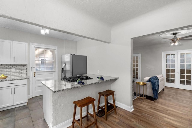 kitchen with white cabinetry, light stone countertops, dark hardwood / wood-style floors, and appliances with stainless steel finishes