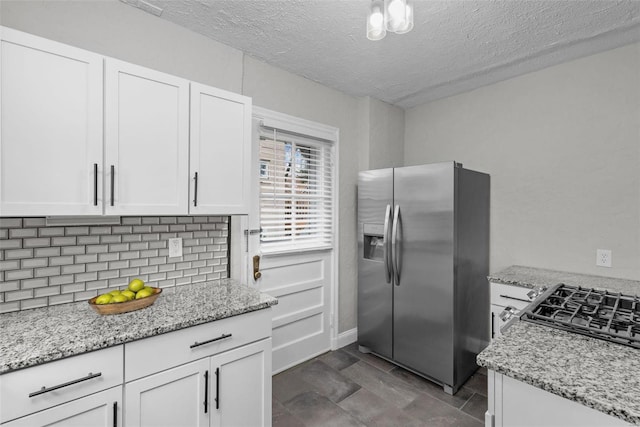 kitchen featuring light stone counters, white cabinetry, stainless steel refrigerator with ice dispenser, and tasteful backsplash