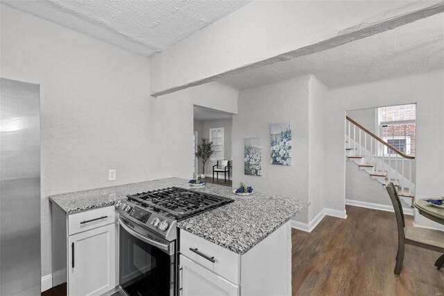 kitchen featuring light stone countertops, a textured ceiling, white cabinetry, and stainless steel gas range oven