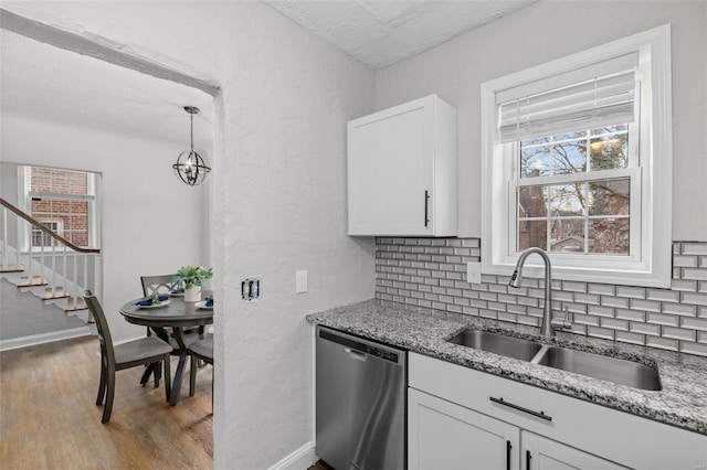 kitchen featuring backsplash, white cabinets, sink, dishwasher, and hanging light fixtures