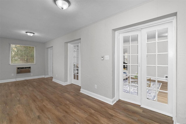 unfurnished living room with a wall mounted air conditioner, dark hardwood / wood-style floors, and french doors