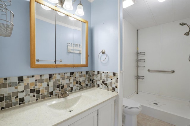 bathroom featuring vanity, a shower, toilet, and backsplash