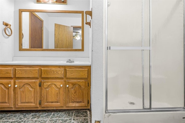 bathroom featuring a shower with shower door and vanity