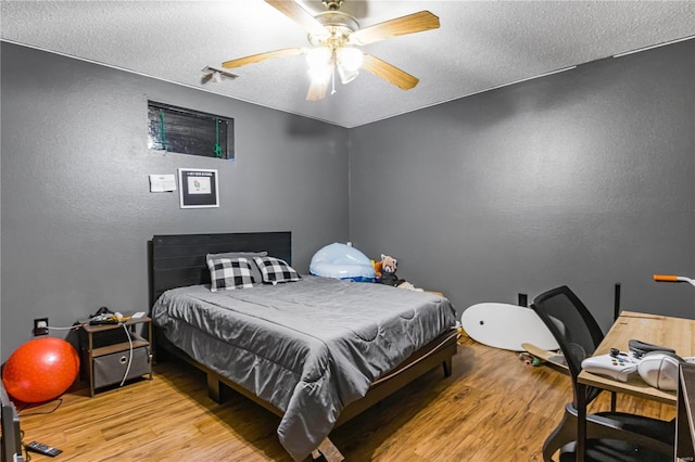 bedroom featuring ceiling fan, a textured ceiling, and light hardwood / wood-style flooring