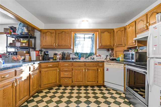 kitchen with a textured ceiling, stainless steel appliances, and sink