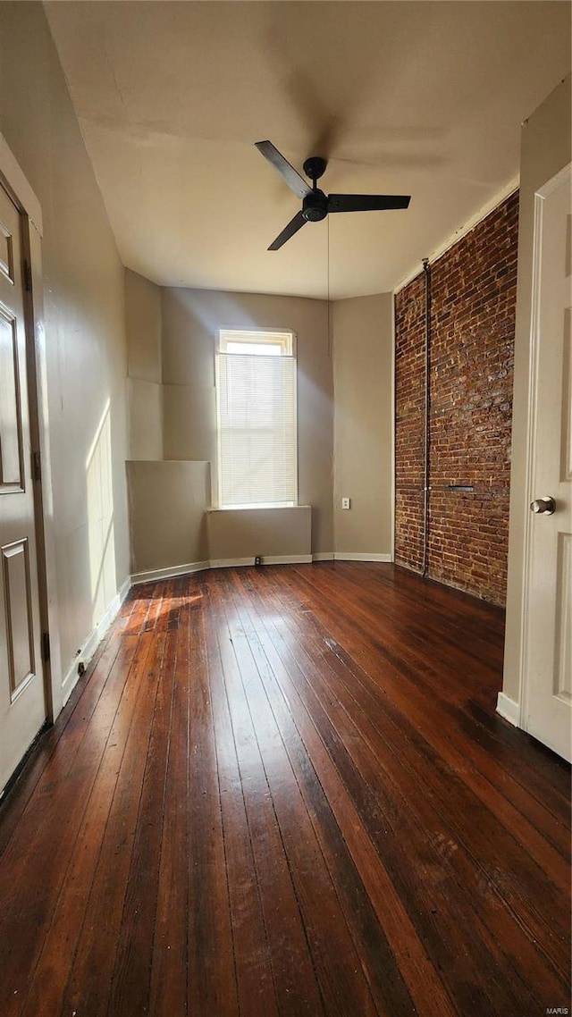 unfurnished bedroom featuring ceiling fan, dark wood-type flooring, and brick wall