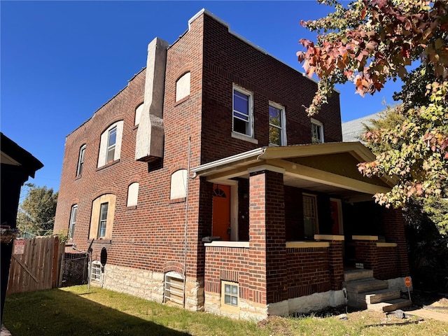 view of side of property with a porch and a lawn