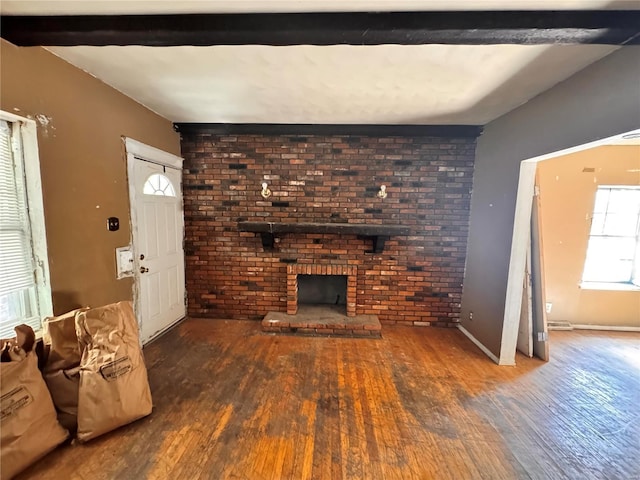 unfurnished living room with brick wall, beam ceiling, a fireplace, and wood-type flooring