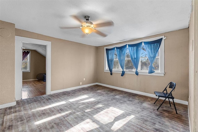 interior space with ceiling fan, wood-type flooring, lofted ceiling, and a textured ceiling