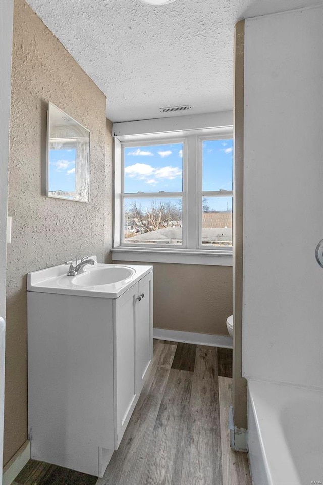 bathroom featuring a textured ceiling, vanity, hardwood / wood-style flooring, and toilet