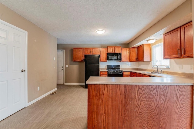 kitchen featuring sink, kitchen peninsula, light hardwood / wood-style floors, a textured ceiling, and black appliances