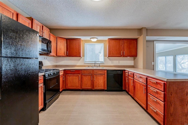 kitchen featuring kitchen peninsula, a wealth of natural light, sink, and black appliances