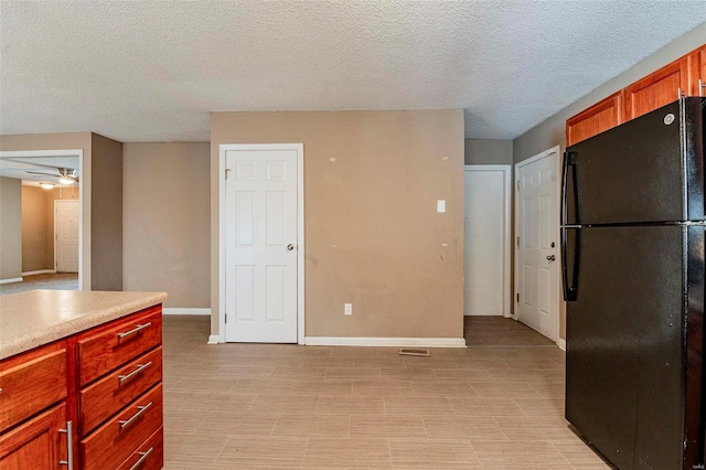 kitchen with ceiling fan, black fridge, and a textured ceiling