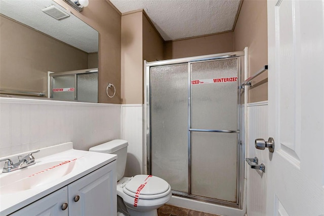 bathroom featuring vanity, a textured ceiling, toilet, and walk in shower