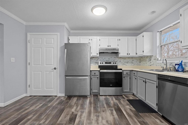 kitchen with dark hardwood / wood-style flooring, ornamental molding, stainless steel appliances, sink, and white cabinetry