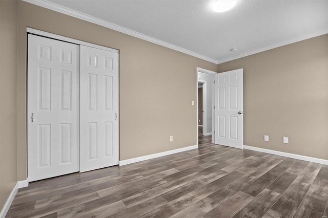 unfurnished bedroom featuring a textured ceiling, hardwood / wood-style flooring, a closet, and crown molding