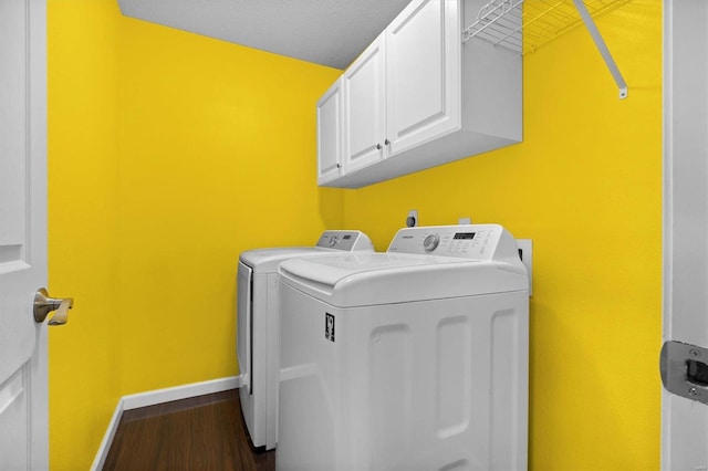 laundry room with dark hardwood / wood-style flooring, washer and clothes dryer, and cabinets