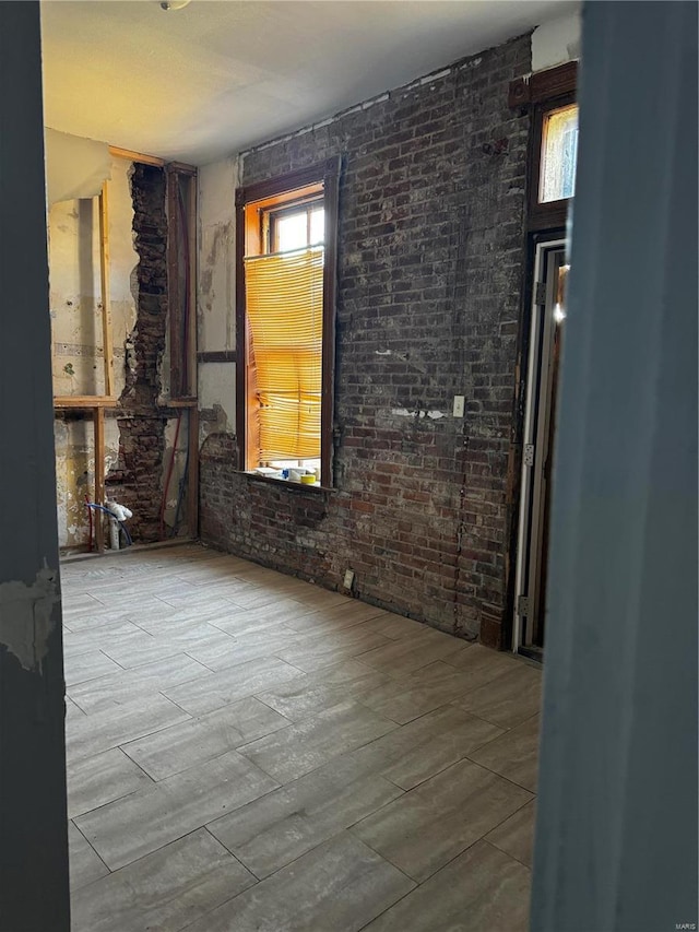 empty room with a healthy amount of sunlight and brick wall