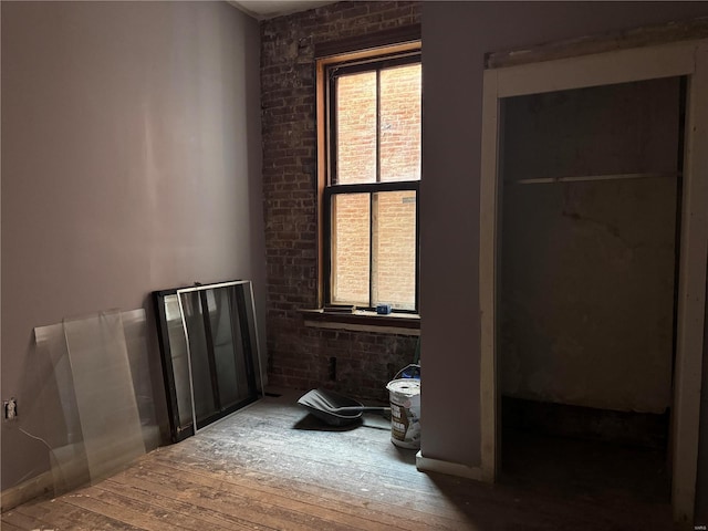 bedroom featuring wood-type flooring and brick wall