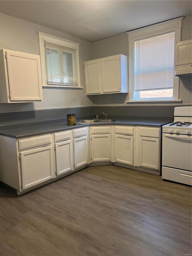 kitchen with white cabinets, white range oven, sink, and dark wood-type flooring