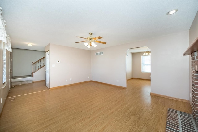 unfurnished living room with a brick fireplace, light hardwood / wood-style flooring, and ceiling fan