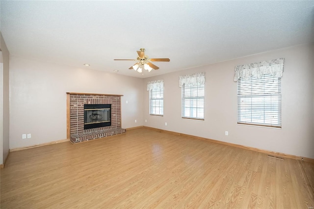 unfurnished living room with a textured ceiling, ceiling fan, light hardwood / wood-style floors, and a fireplace