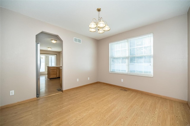 empty room featuring a chandelier and light hardwood / wood-style flooring