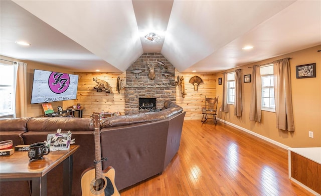 living room with a fireplace, hardwood / wood-style flooring, vaulted ceiling, and wood walls