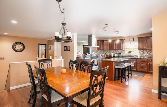 dining room with light wood-type flooring, a notable chandelier, and sink