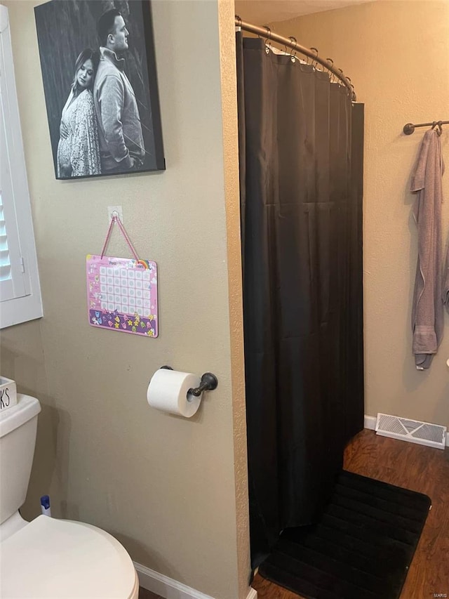 bathroom featuring hardwood / wood-style flooring, toilet, and walk in shower