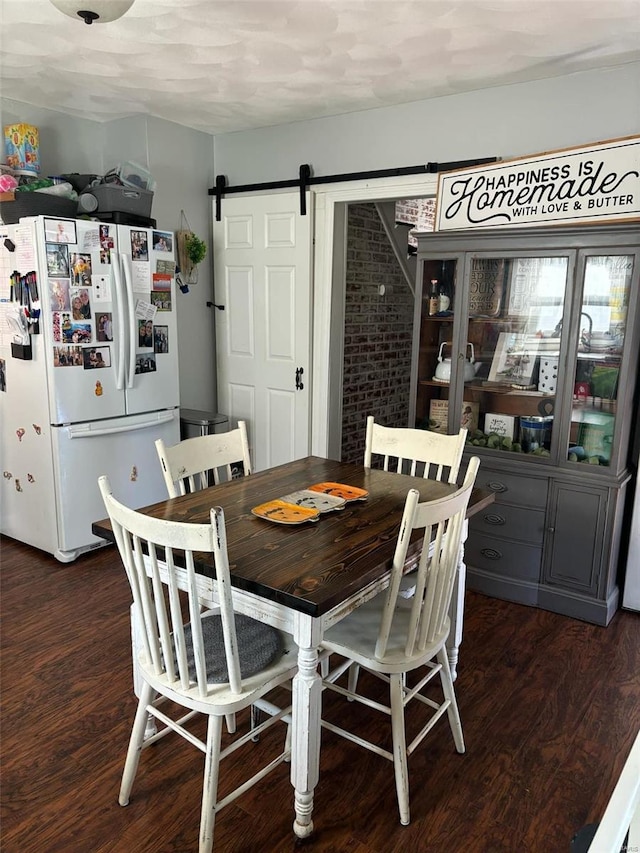 dining space featuring a barn door and dark wood-type flooring