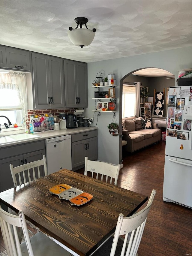 kitchen with white appliances, dark wood-type flooring, a healthy amount of sunlight, and gray cabinetry