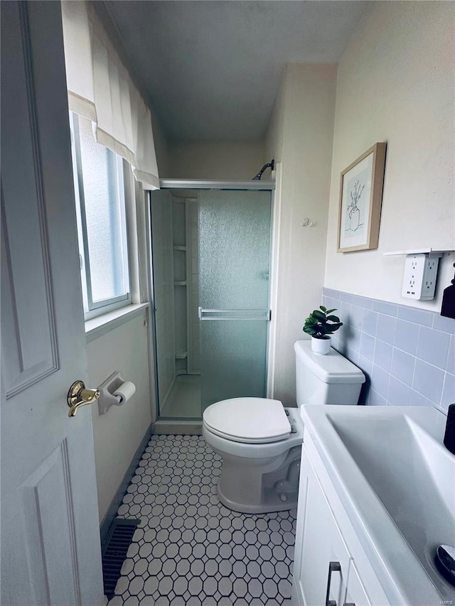 bathroom featuring toilet, tile patterned floors, tile walls, and a shower with shower door