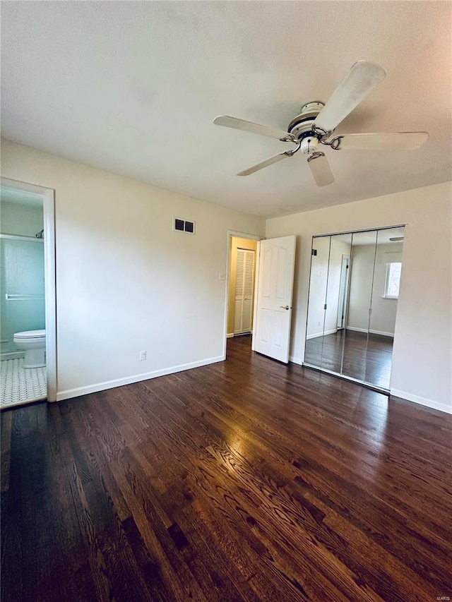 unfurnished bedroom featuring a closet, dark hardwood / wood-style flooring, ensuite bathroom, and ceiling fan