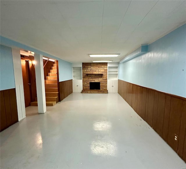 basement with wood walls and a stone fireplace