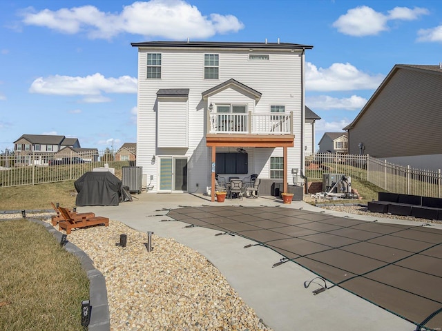 rear view of property featuring cooling unit, a patio area, and a balcony