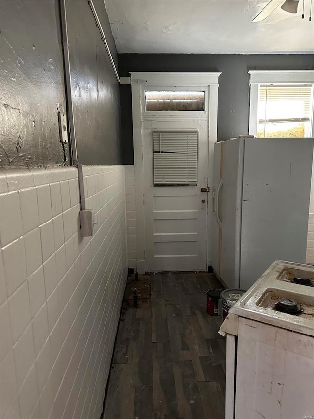 interior space with hardwood / wood-style floors, ceiling fan, and tile walls